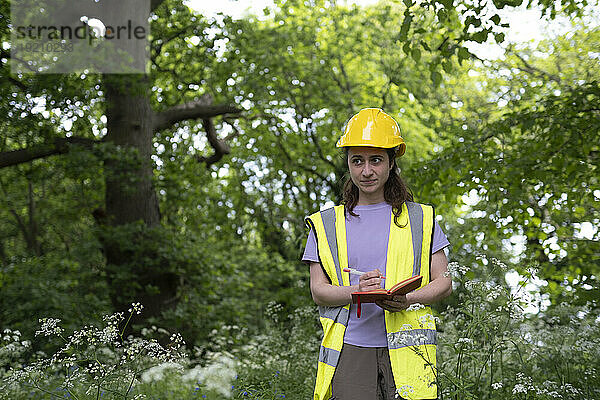 Arbeiter steht und schreibt Tagebuch im Wald