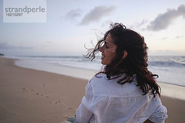 Happy woman with tousled hair at beach