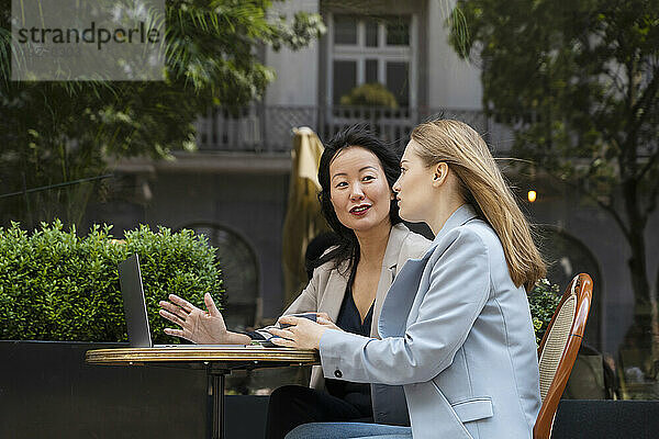Geschäftspartner diskutieren mit Laptop am Tisch im Straßencafé