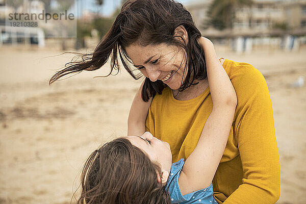 Fröhliche Frau genießt mit Tochter am Strand