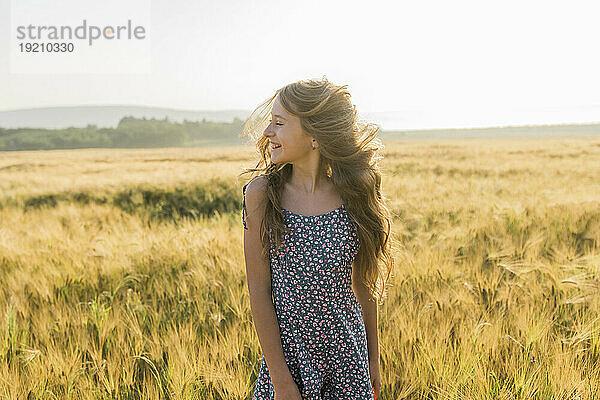 Fröhliches Mädchen mit zerzausten Haaren im Weizenfeld
