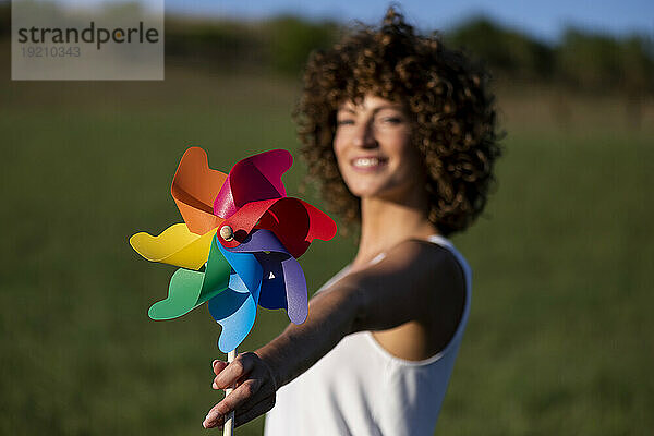 Glückliche Frau mit mehrfarbigem Windradspielzeug