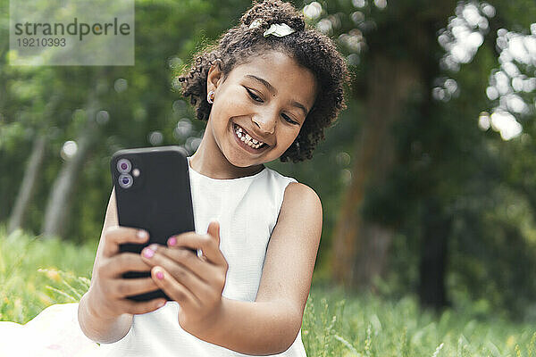 Happy girl taking selfie with smart phone in garden