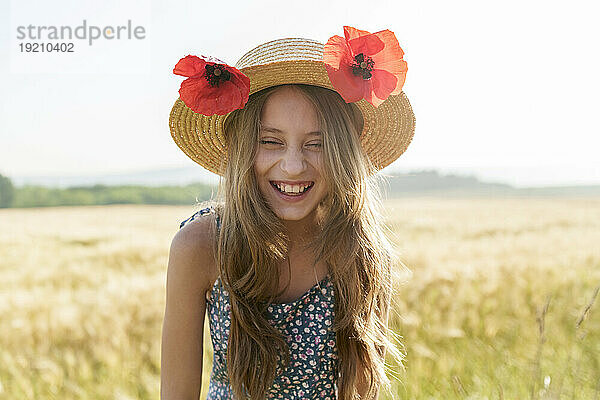 Fröhliches Mädchen mit Hut und roten Mohnblumen auf dem Feld