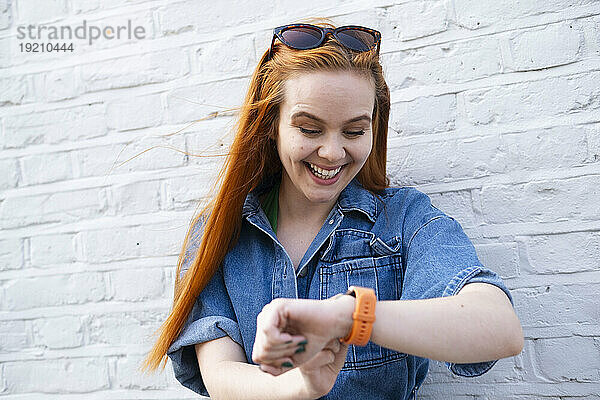 Lächelnde Geschäftsfrau  die die Zeit auf der Armbanduhr überprüft