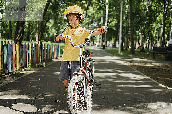 Junge fährt Fahrrad auf Fußweg im Park