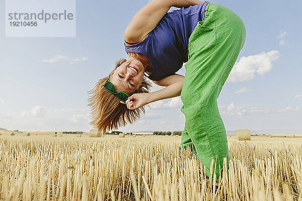 Lächelnde Frau beugt sich im Weizenfeld