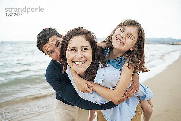 Fröhliche Familie  die gemeinsam Spaß am Strand hat