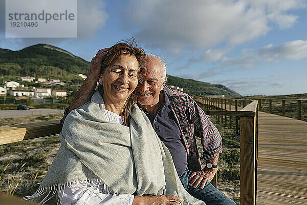 Glückliches Paar  das an einem sonnigen Tag an der Promenade sitzt