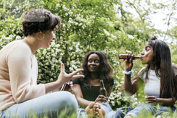 Woman talking with friends drinking beer at park