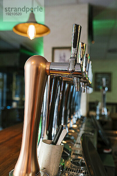 Glänzende Brauereizapfhähne hintereinander im Pub