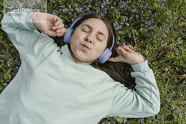 Lächelndes Mädchen  das auf Gras liegt und Musik hört