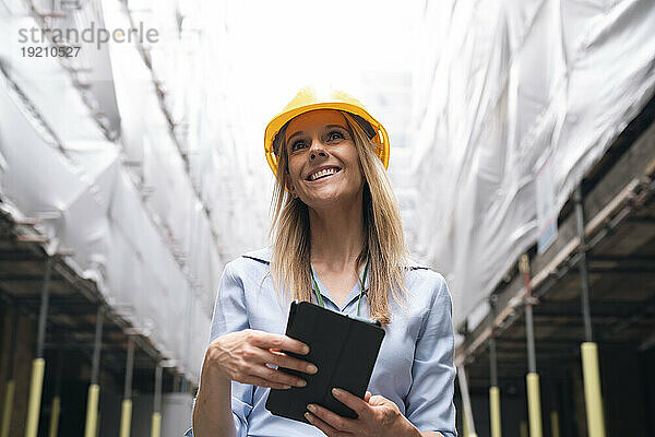 Lächelnder Ingenieur hält Tablet-PC auf der Baustelle