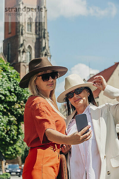 Lächelnde Geschäftsfrau  die an einem sonnigen Tag ein Selfie mit einer Freundin macht