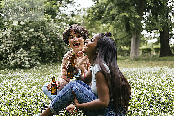 Young friends holding beer and laughing at park