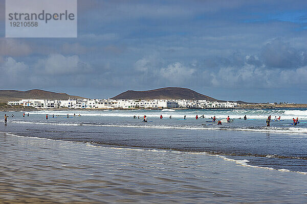 Spanien  Kanarische Inseln  Caleta de Famara  Menschen schwimmen und surfen am Strand Playa de Famara