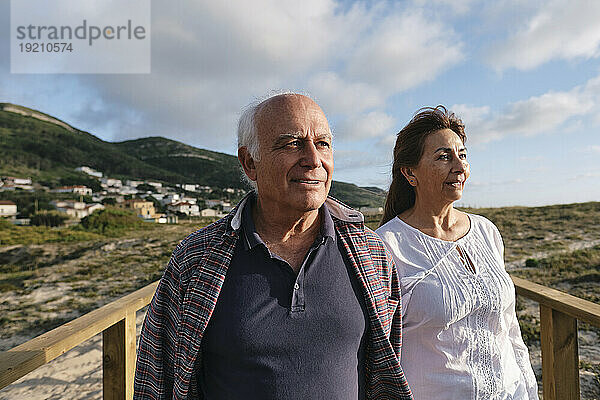 Lächelndes älteres Paar an einem sonnigen Tag unter bewölktem Himmel