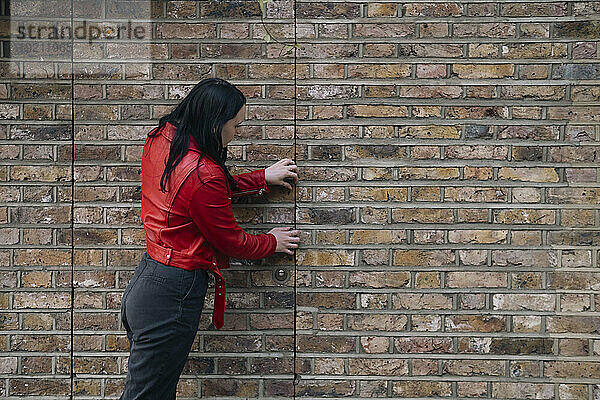 Junge Frau öffnet Tür in der Nähe einer Ziegelmauer