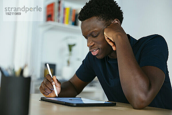 Junge Studentin lernt und schreibt am Schreibtisch auf einem Tablet-PC