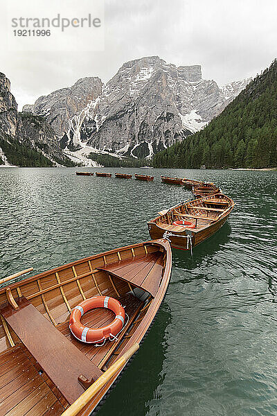 Wooden boats on lake by snow covered mountain