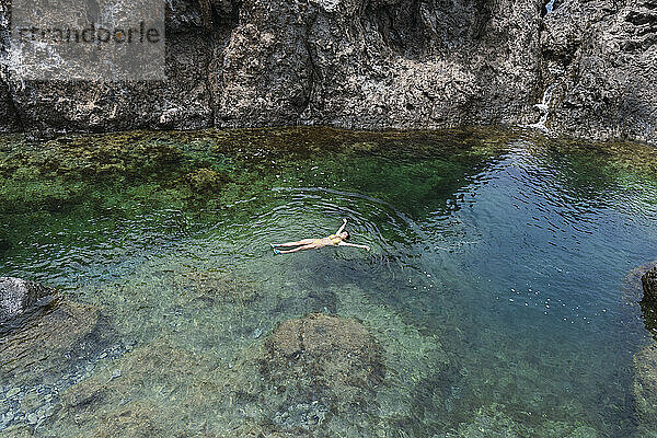 Sorglose Frau schwimmt im Meer in der Nähe von Felsen