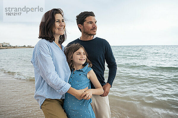 Glückliche Frau steht mit ihrer Familie am Strand