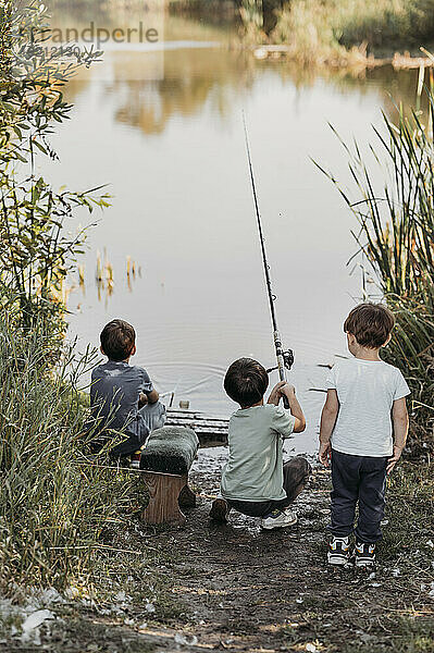 Children fishing together at lakeshore on weekend