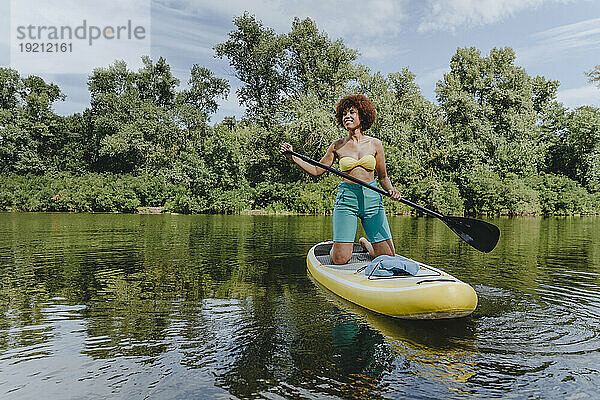 Junge Frau paddelt auf einem Paddleboard im See