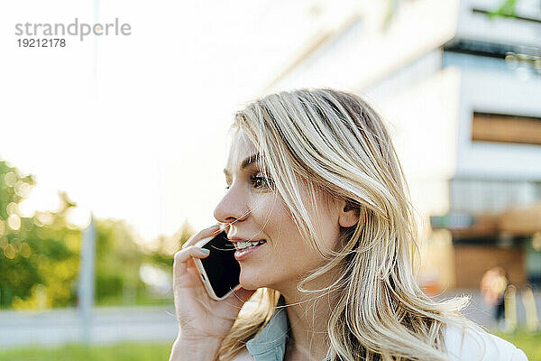 Lächelnde Frau  die draußen mit dem Smartphone spricht