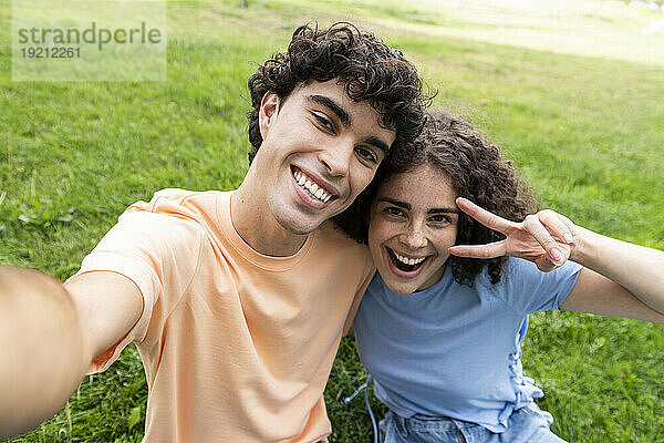Glücklicher Freund und Freundin machen Selfie auf Gras im Park