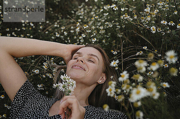 Frau mit der Hand im Haar liegt auf Blumen