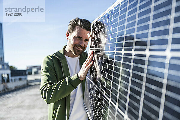 Lächelnder Ingenieur untersucht Solarpanel an sonnigem Tag