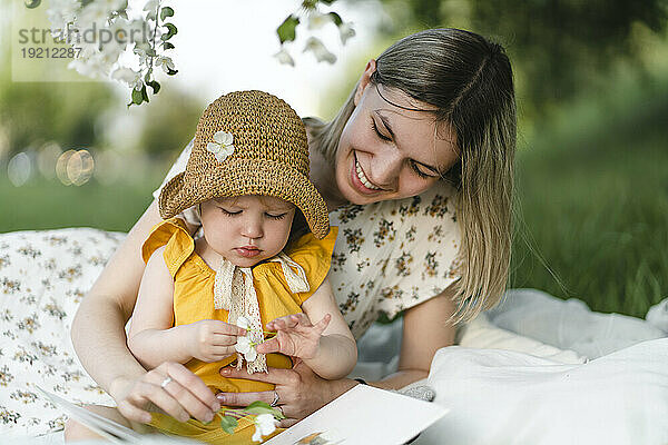 Smiling mother and daughter spending leisure time in garden