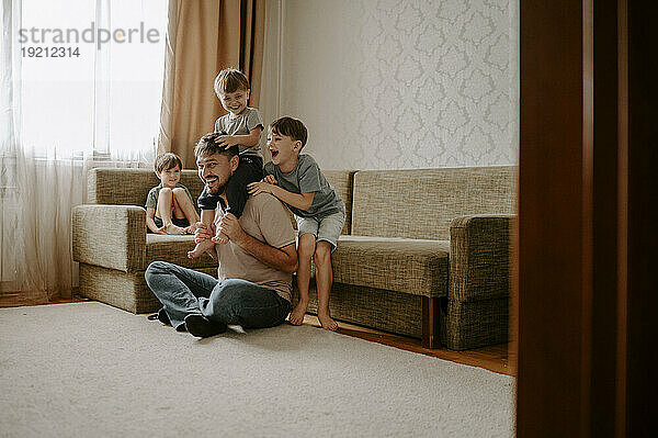 Father and sons spending leisure time on carpet at home
