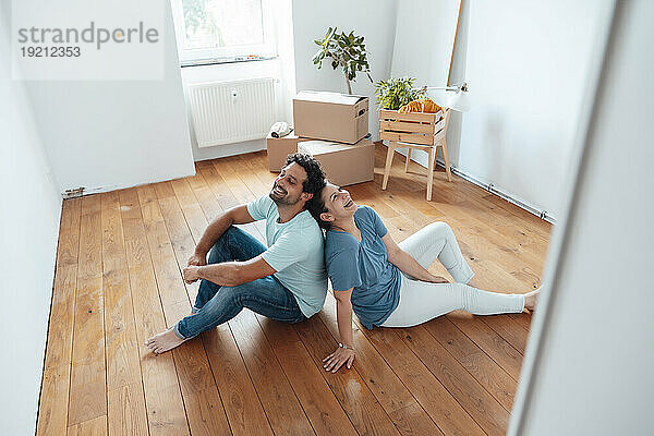 Glückliches Paar sitzt zu Hause auf dem Boden