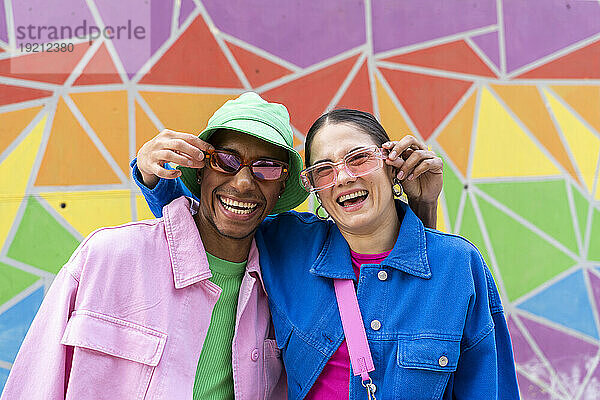 Fröhliches Paar mit Sonnenbrille vor bunter Wand