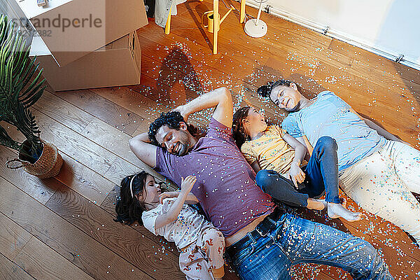 Glückliche Familie  die zu Hause mit Konfetti auf dem Boden liegt