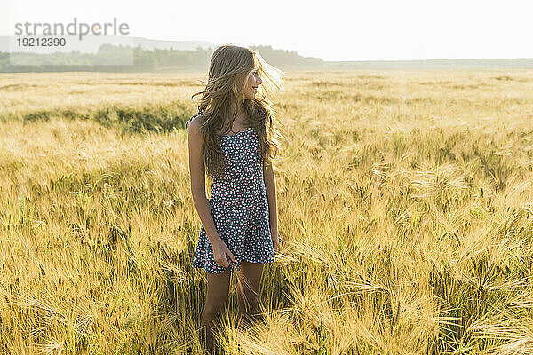 Lächelndes Mädchen mit langen Haaren im Weizenfeld