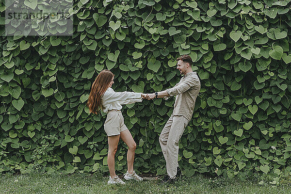 Young couple dancing in front of plants in garden