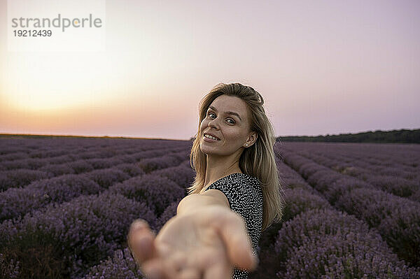 Lächelnde Frau gestikuliert im Lavendelfeld