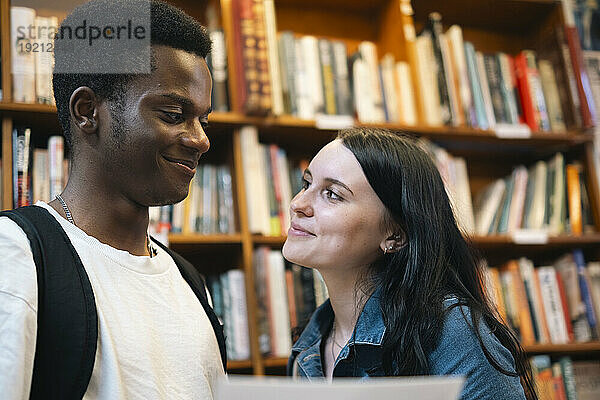Smiling man and woman looking at each other in library