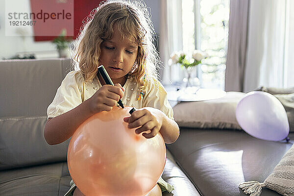 Girl drawing on balloon at home