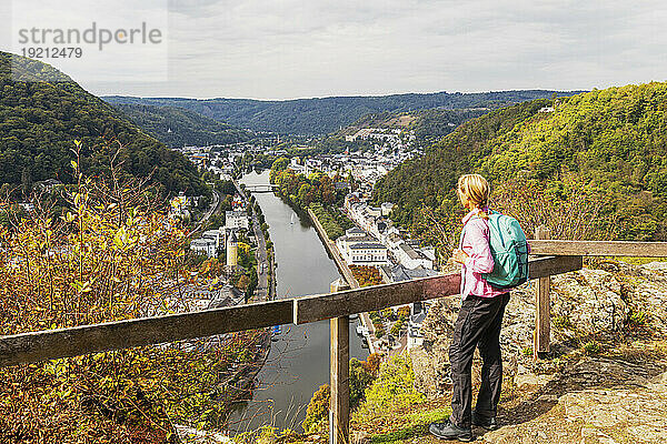 Germany  Rhineland-Palatinate  Bad Ems  Female hiker standing on hilltop overlooking spa town on Lahn river
