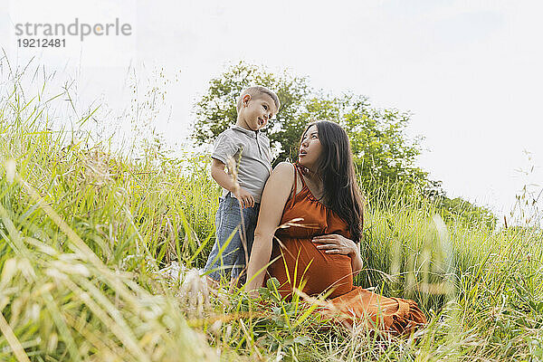 Pregnant mother looking at son in meadow