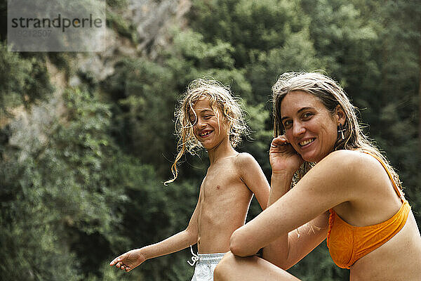 Smiling mother and son spending leisure time in forest