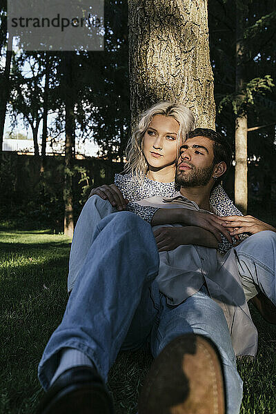 Loving young couple sitting in front of tree