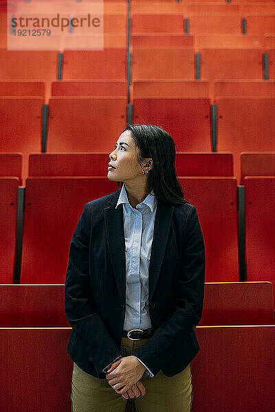 Businesswoman standing in front of red seats at auditorium