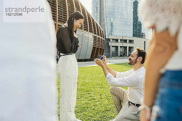 Lächelnder Mann macht Frau mit Ring im Park einen Heiratsantrag