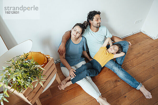 Thoughtful woman sitting with man and daughter lying on lap at home