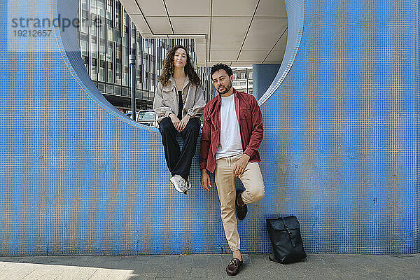 Mann und Frau sitzen auf der Mauer am Fußweg